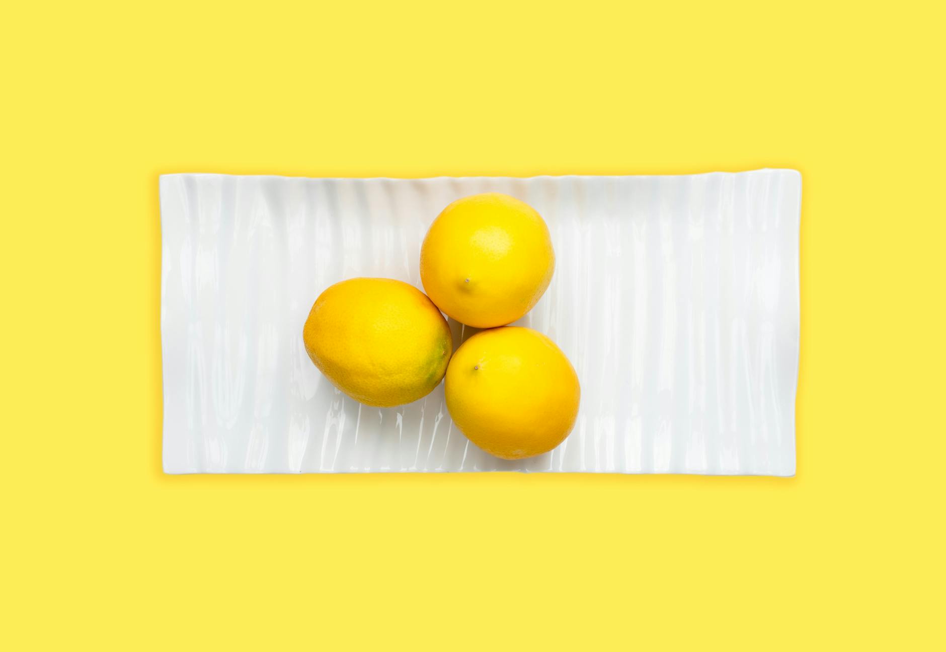 Fresh lemons arranged on white plate with yellow background symbolizing vibrant connection
