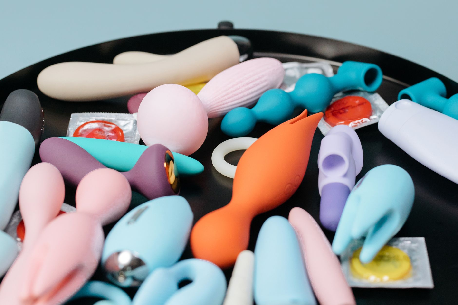 A collection of colorful sex toys displayed on a black tray, representing diverse pleasure options for couples