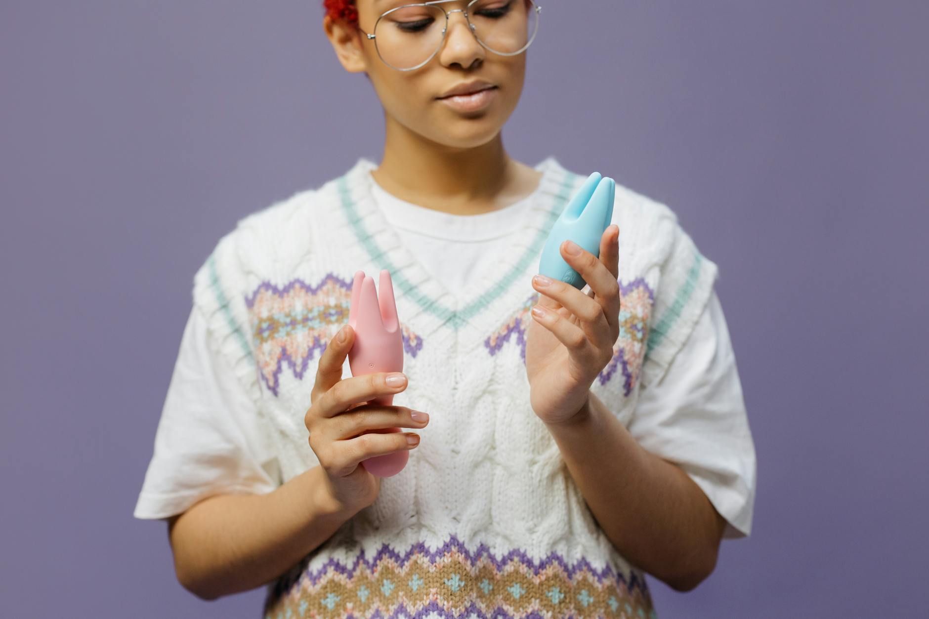 Hands holding pastel-colored silicone toys demonstrating a lemon vibrator for sensation play