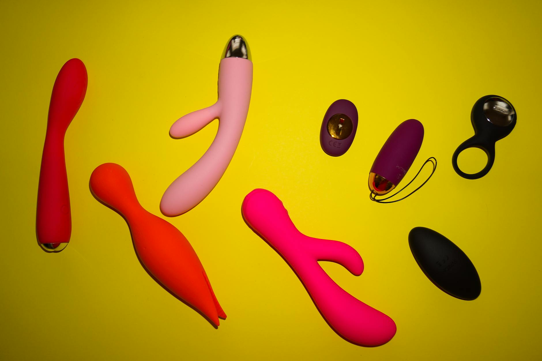 Colorful sex toys arranged on a bright yellow surface, representing diverse designs and pleasure options across life stages